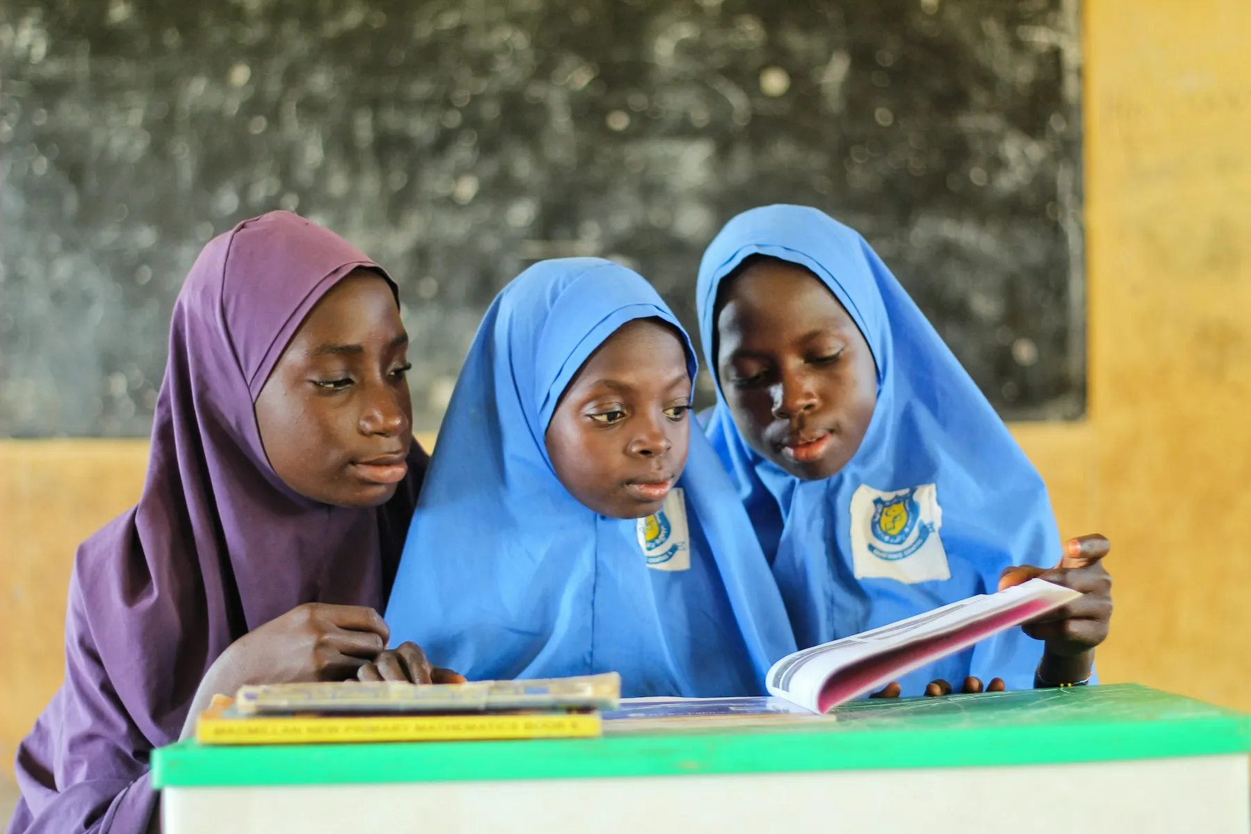 Three schoolgirls reading a book together