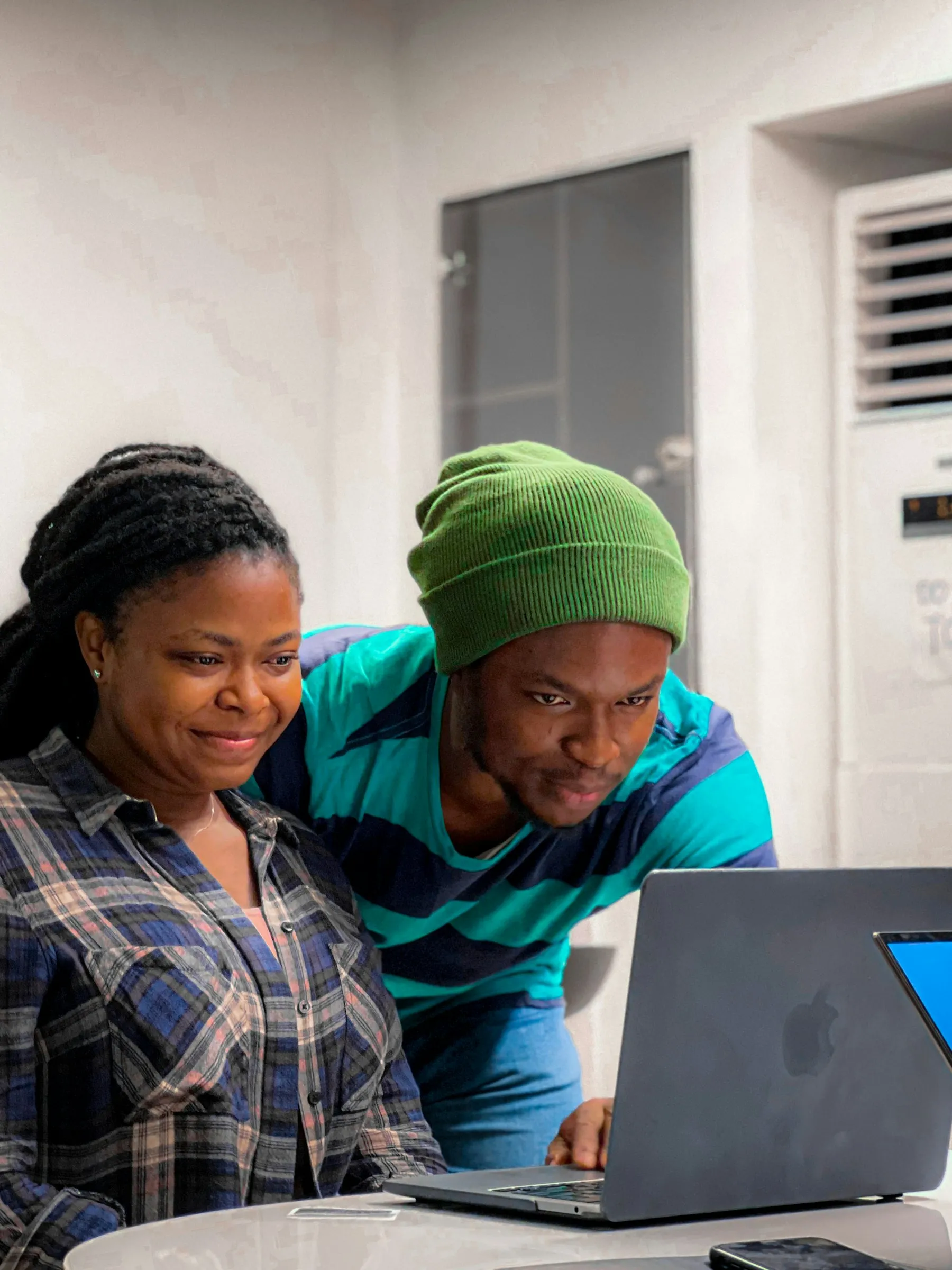 Two volunteers leaning in together to work on a laptop