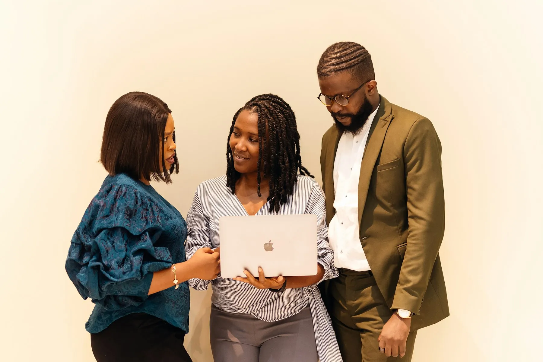 Three colleagues gathered around a laptop, discussing their work